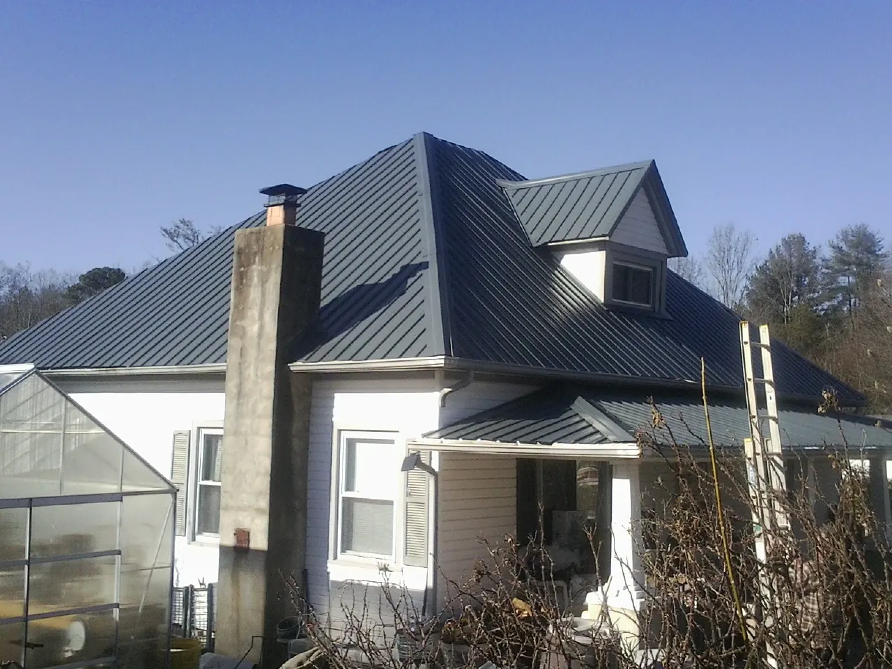 Dark blue standing seam metal roof on a white farmhouse with dormer — Slate & Tile Roof Repair by Roofing Brothers in Pacific City