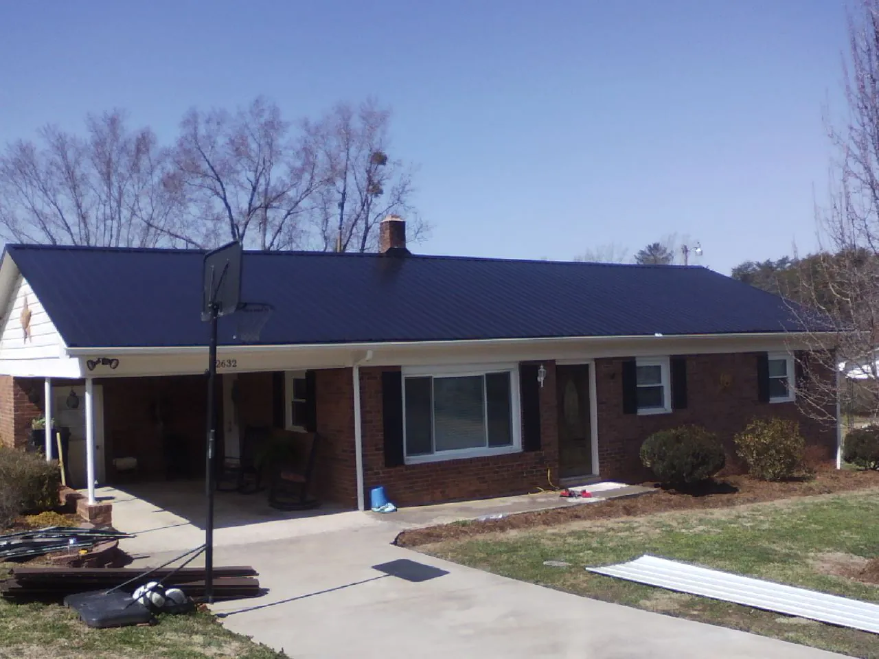 Finished dark blue metal roof on a brick ranch with a carport in Pacific City