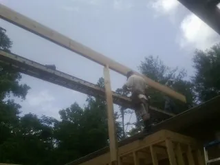 Carpenter setting a ridge beam over a new addition frame — Ice Dam Removal by Roofing Brothers in Pacific City