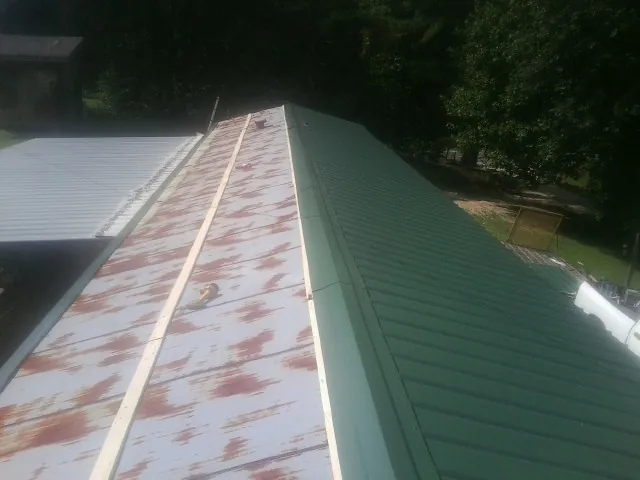 Old rusted panels beside newly installed green metal roofing — Wind Damage Roof Repair by Roofing Brothers in Pacific City