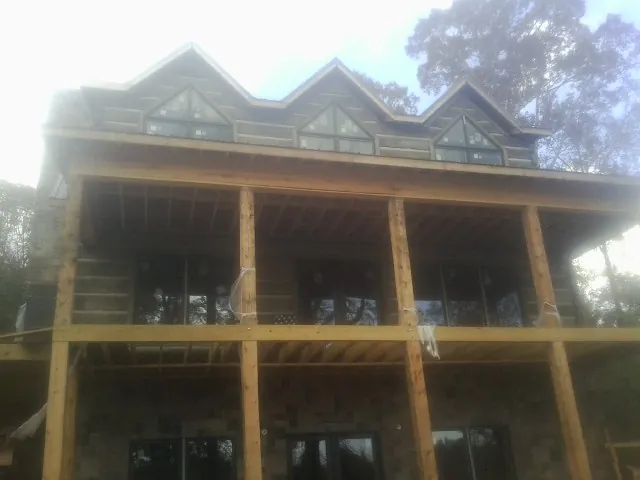 Dormers and porch framing on a large log home under construction — Roof Coating work by our crew in Pacific City