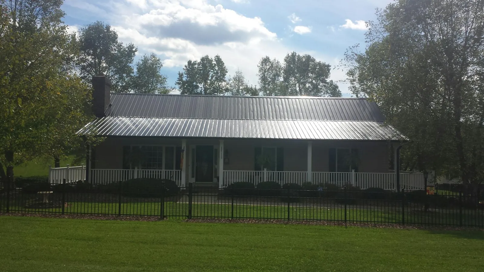 Gray metal roof on a brick ranch with a full width front porch — Gutter Guard Installation work by our crew in Pacific City