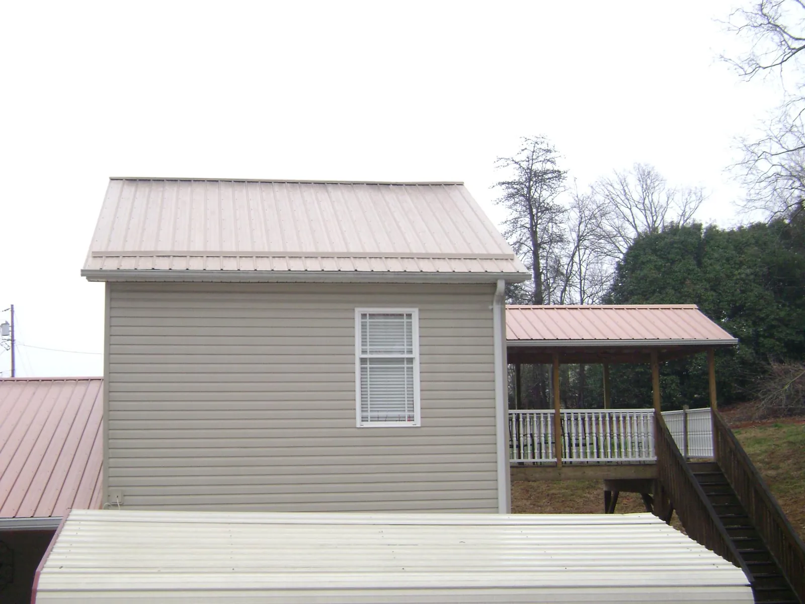 Tan metal roofs on a two story addition and attached porch, from a Roof Replacement job in Pacific City