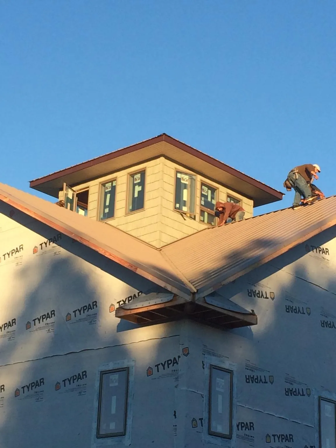 Roofers working around a rooftop cupola on a new metal roof at sunset — Roof Waterproofing in Pacific City by Roofing Brothers